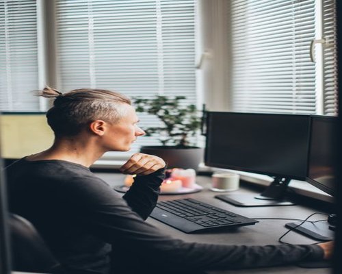 Person looking away from their computer screen towards a window view